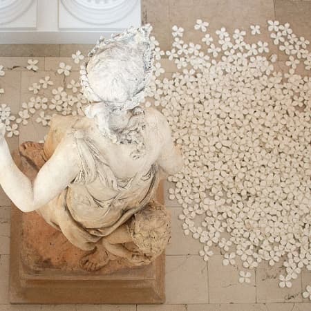 statue on gallery floor with flowers at base